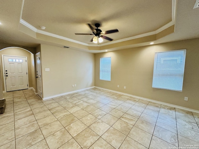 unfurnished room featuring ornamental molding, arched walkways, a raised ceiling, and a ceiling fan