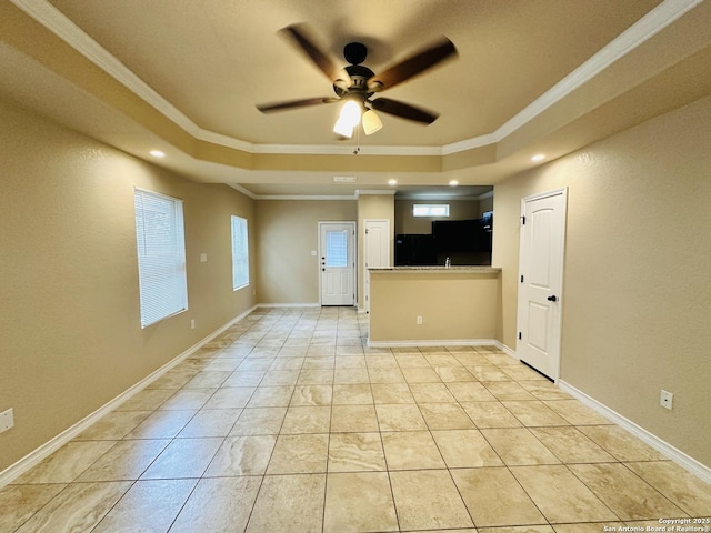 kitchen with baseboards, a raised ceiling, a ceiling fan, crown molding, and light tile patterned flooring