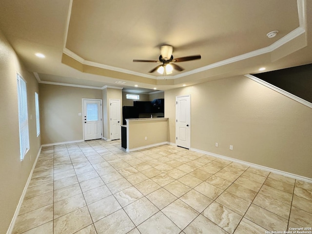 unfurnished living room with ceiling fan, ornamental molding, a raised ceiling, and baseboards