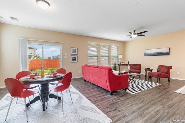 living room featuring baseboards, visible vents, ceiling fan, and dark wood-type flooring