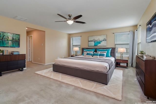 bedroom featuring light carpet, ceiling fan, multiple windows, and visible vents