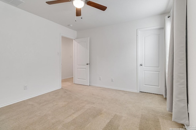 spare room featuring a ceiling fan, light colored carpet, visible vents, and baseboards