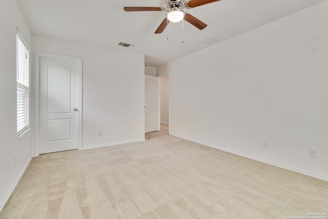 spare room with baseboards, ceiling fan, visible vents, and light colored carpet