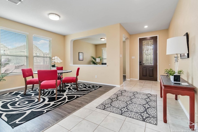 dining room with light tile patterned floors, baseboards, arched walkways, and recessed lighting