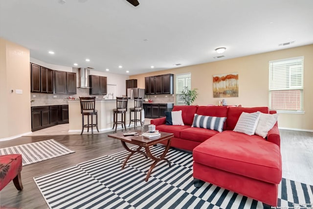 living room with light wood-type flooring, visible vents, baseboards, and recessed lighting