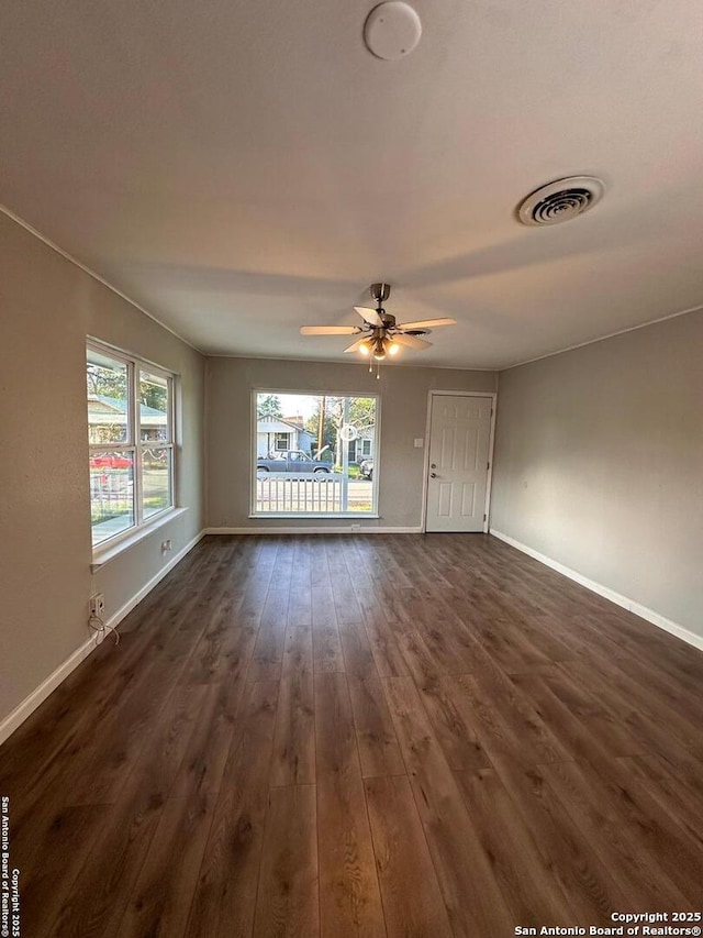 unfurnished living room featuring a ceiling fan, dark wood finished floors, visible vents, and baseboards