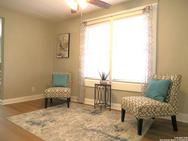 sitting room with a ceiling fan, baseboards, and wood finished floors