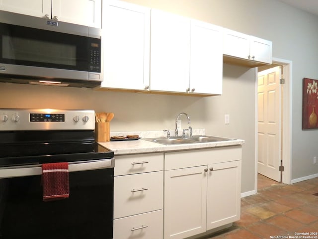 kitchen featuring stainless steel appliances, a sink, white cabinetry, baseboards, and light countertops