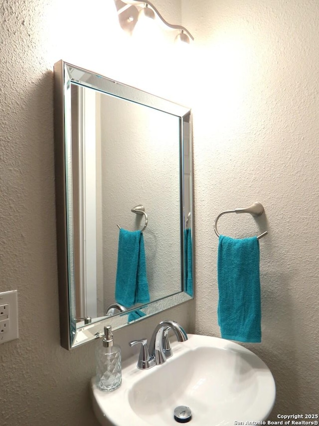 bathroom featuring a textured wall and a sink