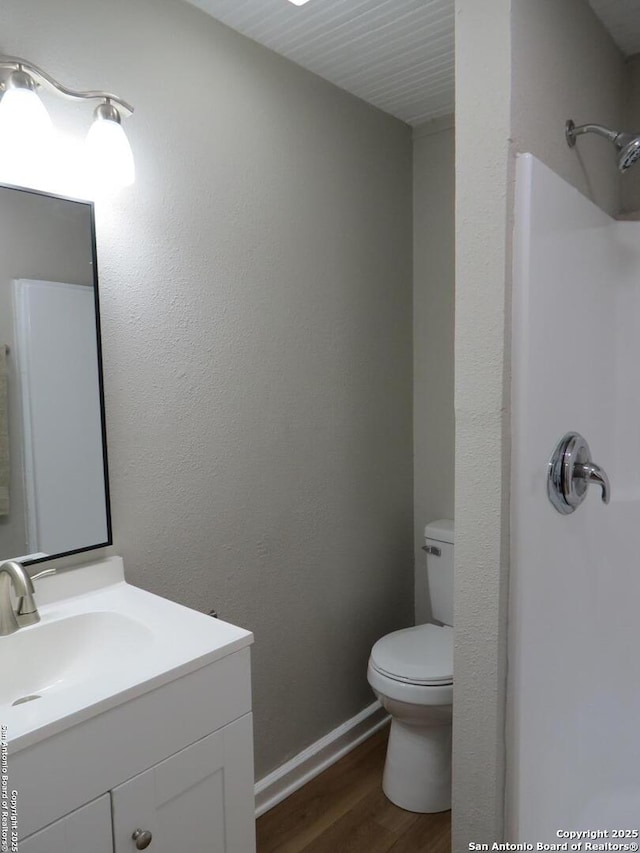 bathroom with toilet, baseboards, wood finished floors, and vanity