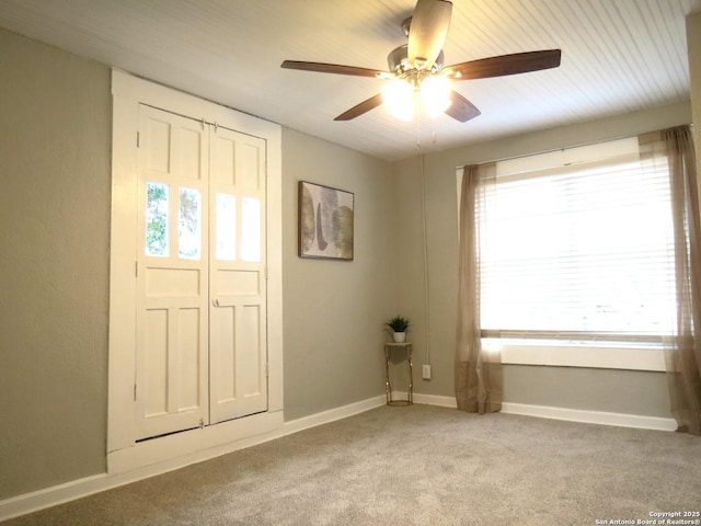 entryway with ceiling fan, baseboards, and light colored carpet