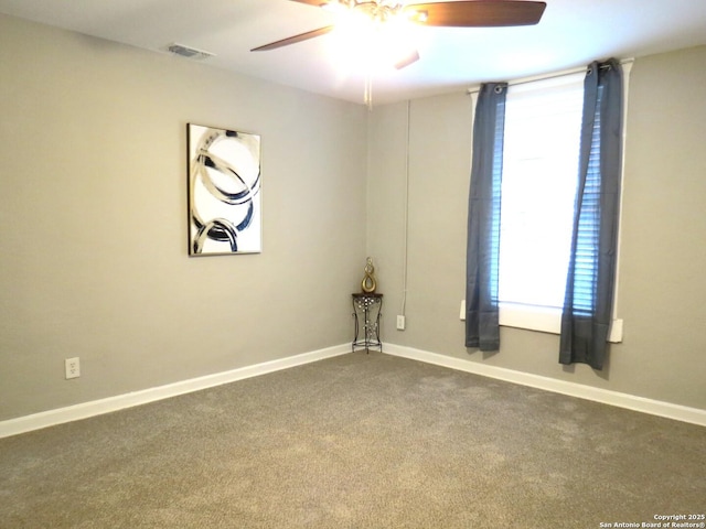 empty room with ceiling fan, dark carpet, visible vents, and baseboards