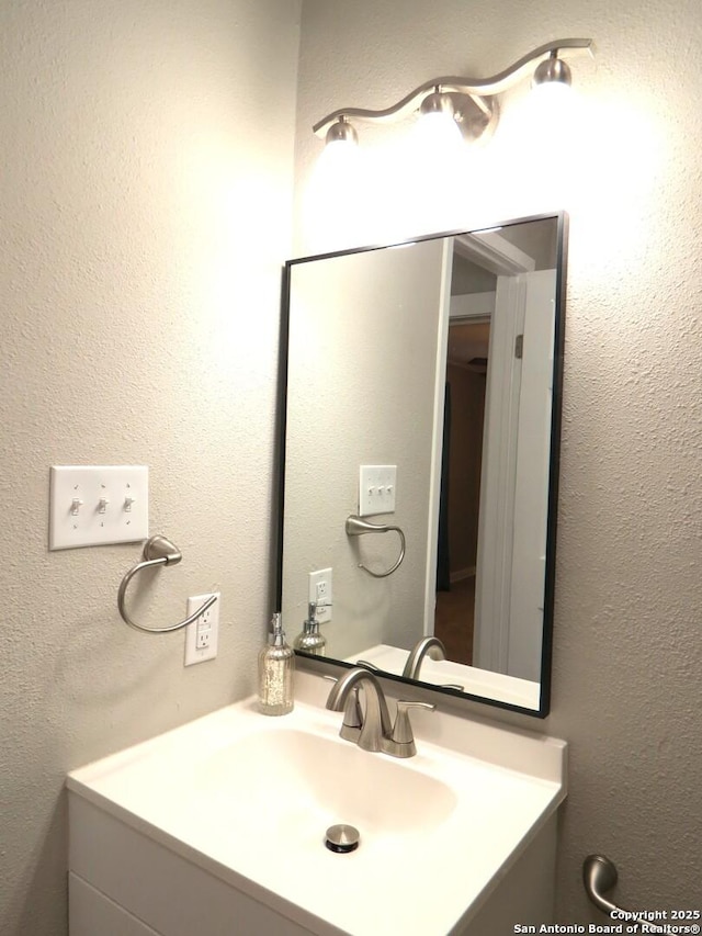 bathroom with a textured wall and vanity