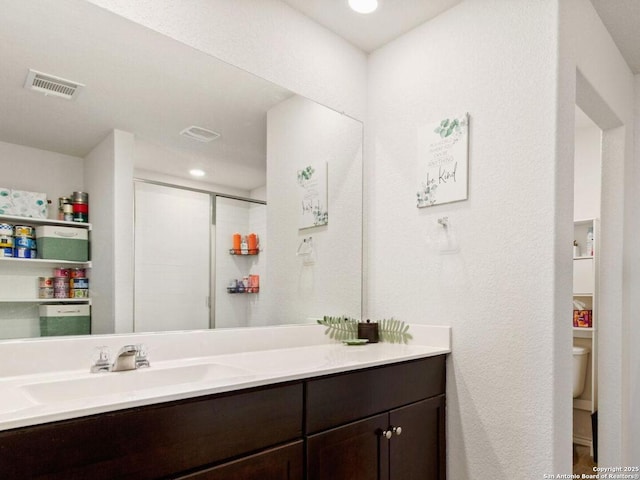 full bathroom featuring toilet, a stall shower, visible vents, and vanity