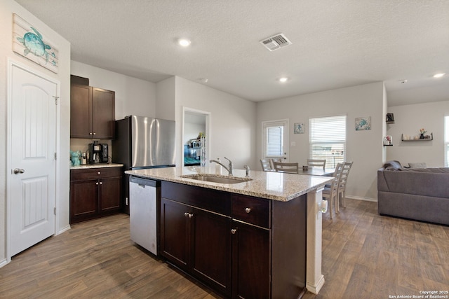 kitchen featuring a center island with sink, stainless steel appliances, visible vents, open floor plan, and a sink