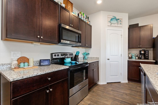 kitchen featuring stainless steel appliances, dark brown cabinets, dark wood-style floors, and light stone countertops