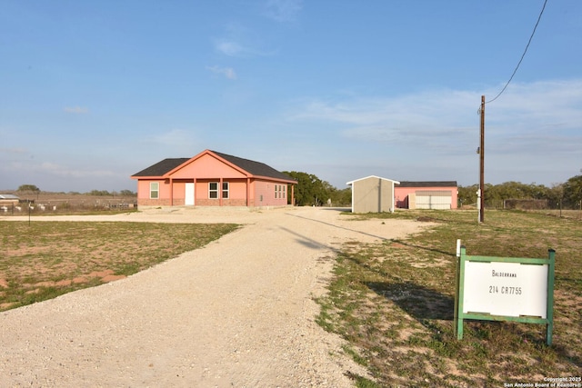 view of front of home with a garage, driveway, a front lawn, and an outdoor structure