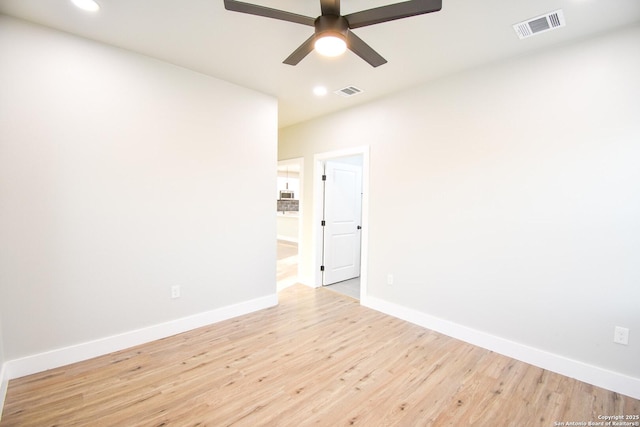 spare room with light wood-style floors, baseboards, visible vents, and a ceiling fan