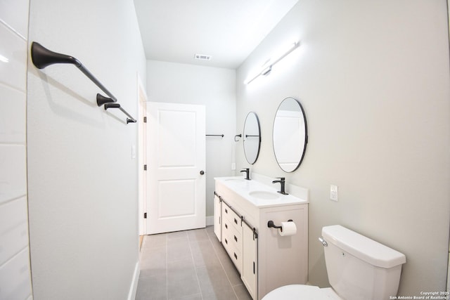 bathroom featuring double vanity, visible vents, toilet, tile patterned flooring, and a sink