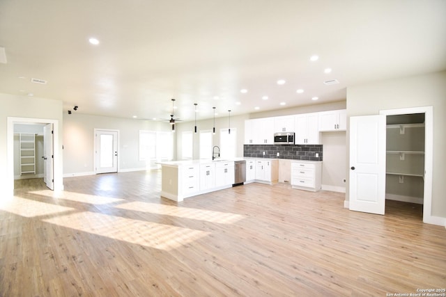 kitchen with light countertops, appliances with stainless steel finishes, open floor plan, white cabinetry, and a sink