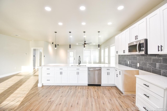 kitchen with appliances with stainless steel finishes, pendant lighting, light countertops, and open floor plan