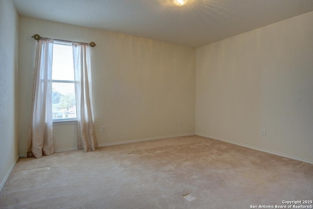 spare room featuring baseboards and light colored carpet