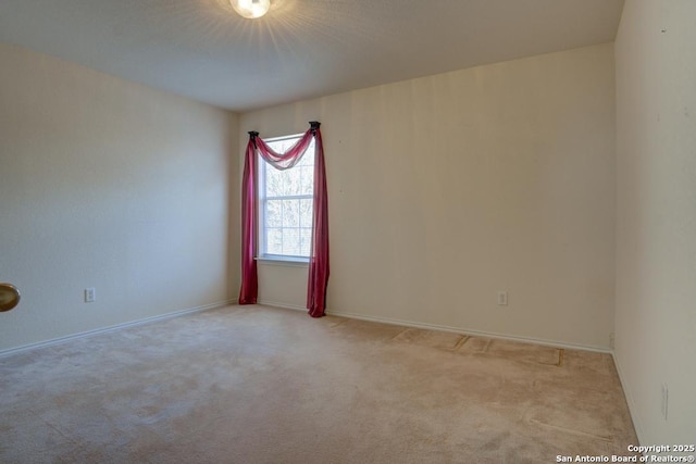 empty room featuring light colored carpet and baseboards