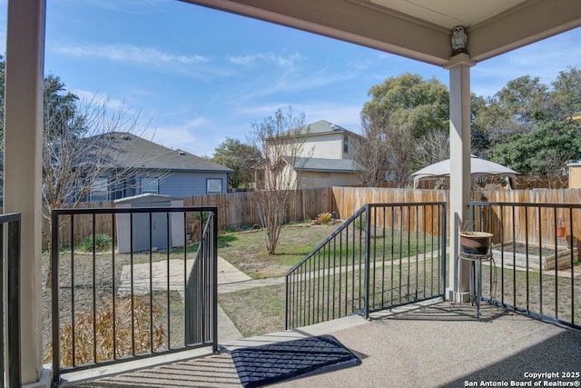 view of gate with a fenced backyard, a lawn, an outdoor structure, and a shed