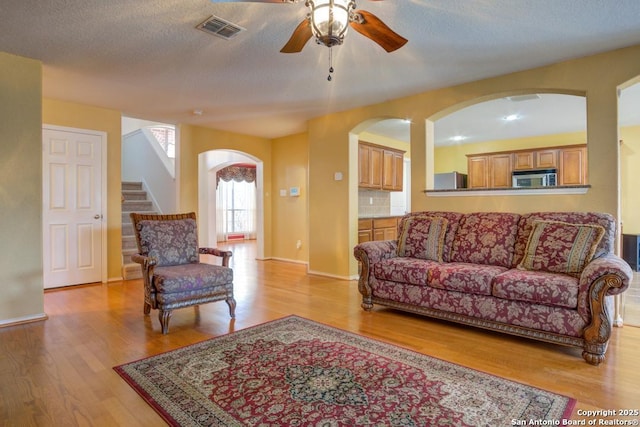living room featuring visible vents, stairway, and light wood finished floors