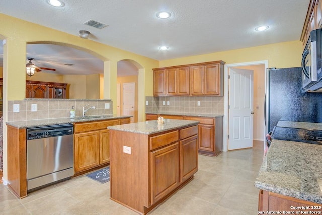 kitchen with stainless steel appliances, brown cabinets, visible vents, and a center island