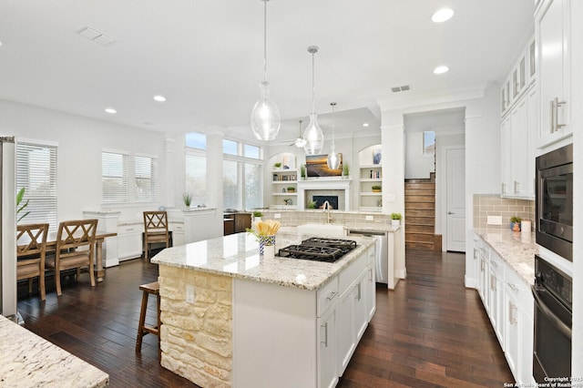 kitchen featuring recessed lighting, dark wood-type flooring, a fireplace, a center island, and black appliances