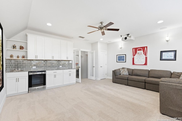 living room with recessed lighting, light colored carpet, a ceiling fan, vaulted ceiling, and beverage cooler