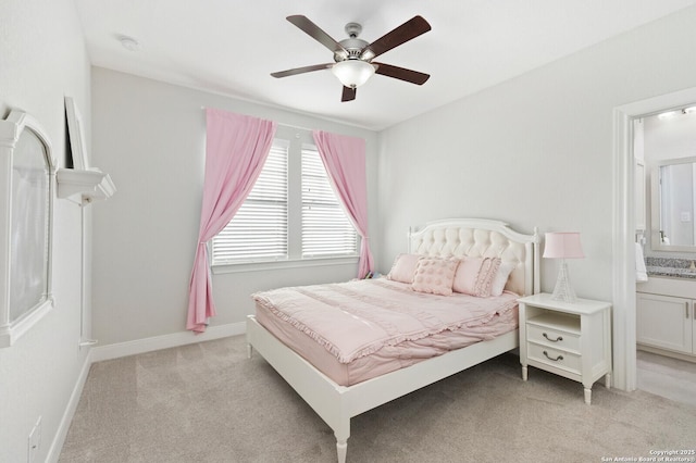 bedroom featuring baseboards, ensuite bath, a ceiling fan, and light colored carpet