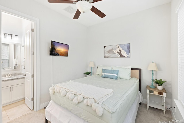 bedroom with light colored carpet, a sink, ceiling fan, ensuite bath, and baseboards