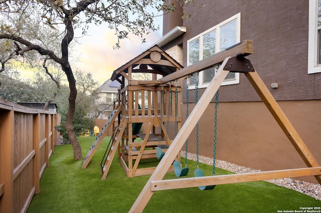 playground at dusk featuring fence private yard, a playground, and a lawn