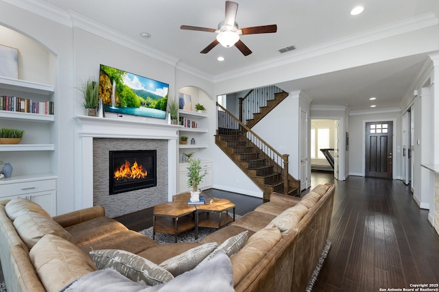 living area featuring built in shelves, visible vents, ornamental molding, and dark wood-type flooring