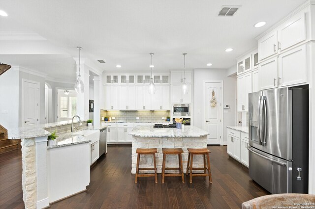 kitchen with appliances with stainless steel finishes, visible vents, a kitchen island, and a kitchen breakfast bar