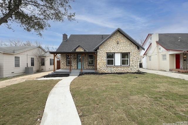 view of front facade with covered porch, a front lawn, a chimney, and central AC unit