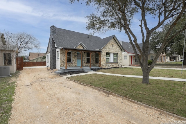 view of front of property with central AC, fence, dirt driveway, roof with shingles, and a front lawn