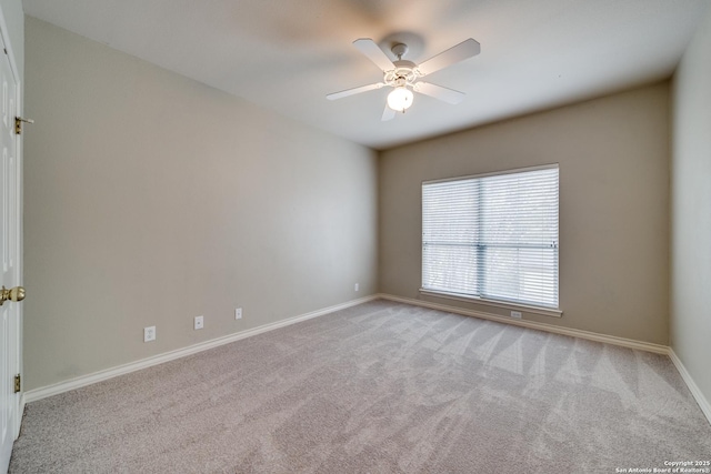 spare room featuring baseboards, a ceiling fan, and light colored carpet