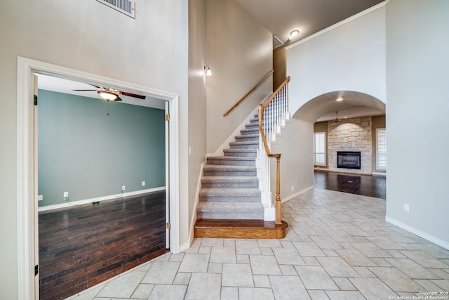 stairway featuring arched walkways, visible vents, a towering ceiling, a ceiling fan, and baseboards