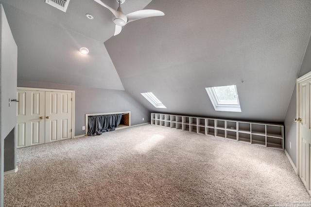 additional living space featuring carpet floors, visible vents, lofted ceiling with skylight, a textured ceiling, and baseboards