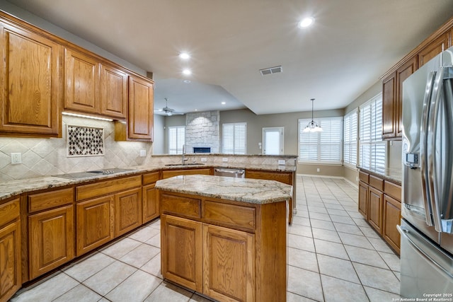 kitchen featuring a center island, pendant lighting, stainless steel appliances, visible vents, and a sink