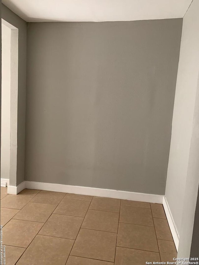 unfurnished room with baseboards and tile patterned floors