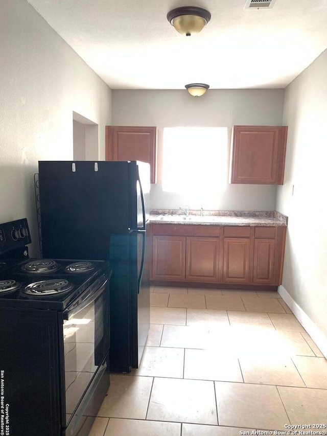 kitchen featuring a sink, visible vents, light countertops, brown cabinets, and black appliances