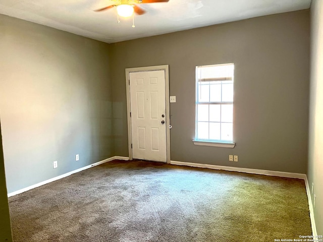 carpeted spare room with ceiling fan and baseboards