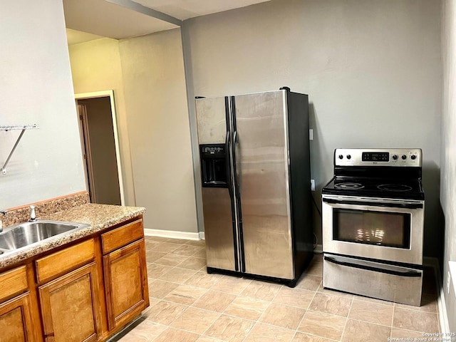 kitchen with brown cabinetry, appliances with stainless steel finishes, light countertops, and a sink