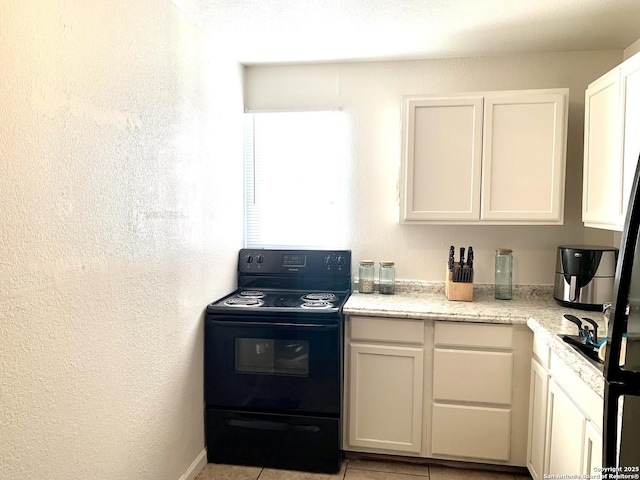 kitchen with black range with electric cooktop, light stone counters, white cabinets, and a textured wall