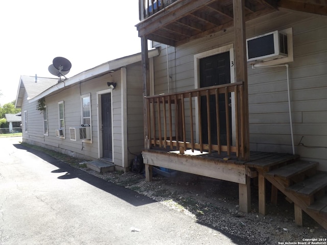 view of side of property featuring cooling unit and a wall mounted air conditioner