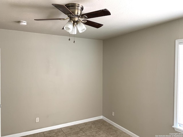 tiled empty room featuring a textured ceiling, a ceiling fan, and baseboards